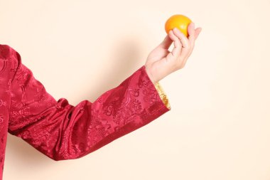 Yeni Çin yılın kutlu olsun. Asya 'nın enerjik son sınıf öğrencisi altın rengi Cheongsam Qipao ya da Changshan elbisesi giyer ve bej arka planda el ele tutuşur..