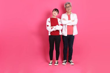 Sevgililer Günü 'nde, Asyalı son sınıf öğrencisi ve genç kadın pembe arka planda duran ve gülümseyen hareketleriyle beyaz kalp şeklinde gömlekli sıradan kırmızı kıyafetler giyerler..