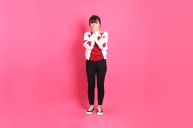 Sevgililer günü, kırmızı tişörtlü Asyalı bir kadın ya da günlük kıyafetler, kırmızı kalp şeklinde gömlek ve pembe arka planda kapalı bir burun. Gen Z