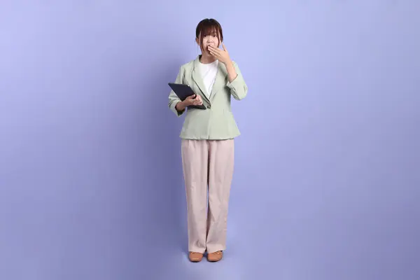 Resmi kıyafetli Asyalı genç bir iş kadını elinde tablet, Mor arka planda kapalı bir ağız. Gen Z, staj, kariyer, ofis.