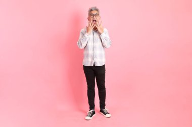 Resmi ve gündelik beyaz gömlekli Asyalı üst düzey bir adam sürpriz jesti ve pembe arka planda etkileyici bir şekilde izole edilmiş..