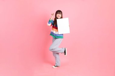 Renkli gökkuşağı kıyafetleri giyen Asyalı bir kadın ya da pembe arka planda boş tuval tutan bir jest. Gen Z