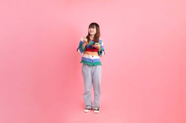 Renkli gökkuşağı kıyafetleri giyen Asyalı bir kadın ya da pembe arka planda saklanmış hediye kutusunu tutan bir jest. Gen Z