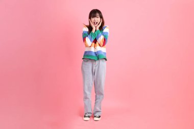 Renkli gökkuşağı kıyafetleri giyen Asyalı bir kadın ya da sürpriz jestli sıradan bir görünüş ve pembe arka planda etkileyici bir izolasyon. Gen Z