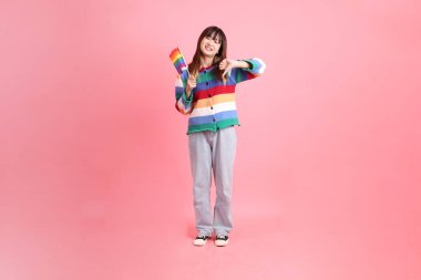 Renkli gökkuşağı kıyafetleri giyen Asyalı bir kadın ya da pembe arka planda Gurur Bayraklarını Tutma jesti olan sıradan görünüşlü bir kadın. Gen Z