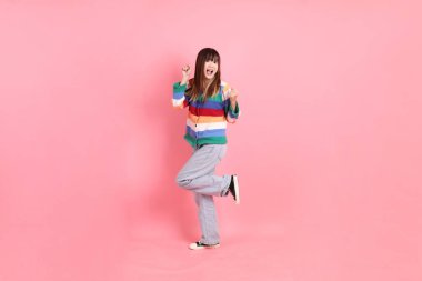 Renkli gökkuşağı kıyafetleri giyen Asyalı bir kadın ya da pembe arka planda izole edilmiş, heyecanlı ve kutlama yapan bir jest. Gen Z