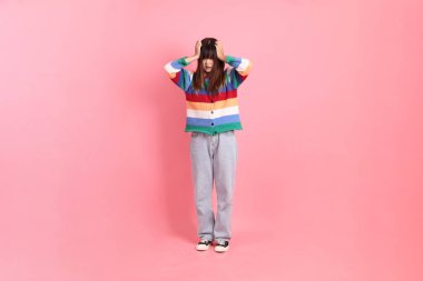Renkli gökkuşağı kış kıyafetleri giyen Asyalı bir kadın ya da pembe arka planda izole edilmiş stres jesti içeren sıradan görünüşlü bir kadın. Gen Z