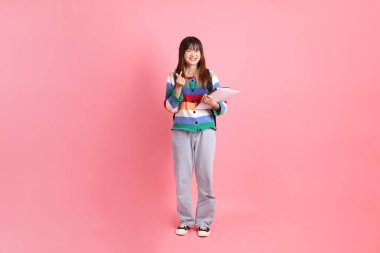 Renkli gökkuşağı kıyafetleri giyen Asyalı bir kadın ya da okul çantası ve kitap taşırken gelişigüzel görünen pembe arka planda sevgi dolu küçük bir kalp. Gen Z