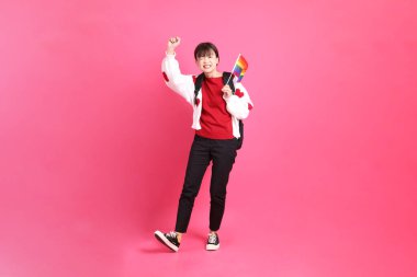 Kırmızı tişörtlü Asyalı bir kadın ya da günlük kıyafetler, kırmızı kalp şeklinde gömlek ve pembe arka planda tutulan Onur Bayrakları jesti. Gen Z LGBTQ + topluluğu