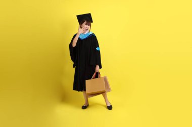 Sarı arka planda, mavi mezuniyet elbiseleri ve kepleri olan, alışveriş çantası taşıyan bir üniversite öğrencisi. Gen Z, yeni mezun, eğitim, ilk iş