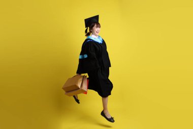 Sarı arka planda, mavi mezuniyet elbiseleri ve kepleri olan, alışveriş çantası taşıyan bir üniversite öğrencisi. Gen Z, yeni mezun, eğitim, ilk iş