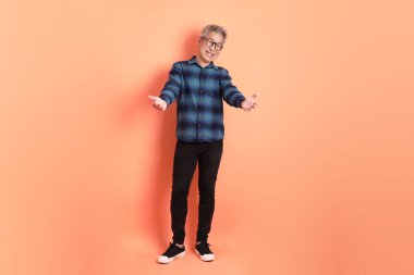 Yeşil ekose giysili Asyalı son sınıf öğrencisi. Gözlük takıyor. Turuncu arka planda izole edilip alınma hareketi yapıyor. Turist, akıllı gündelik.