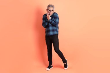 Yeşil ekose giysili, gözlüklü, turuncu arka planda diş ağrısı jesti olan Asyalı son sınıf öğrencisi. Turist, akıllı gündelik.