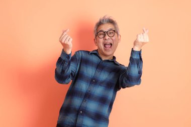 Yeşil ekose elbiseli Asyalı son sınıf öğrencisi. Gözlük takıyor. Kalp şeklinde jestler yapıyor. Turist, akıllı gündelik.