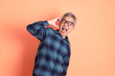 Yeşil ekose elbiseli Asyalı son sınıf öğrencisi. Gözlük takıyor. Kalp şeklinde jestler yapıyor. Turist, akıllı gündelik.