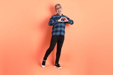 Yeşil ekose elbiseli Asyalı son sınıf öğrencisi. Gözlük takıyor. Kalp şeklinde jestler yapıyor. Turist, akıllı gündelik.