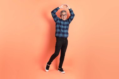 Yeşil ekose elbiseli Asyalı son sınıf öğrencisi. Gözlük takıyor. Kalp şeklinde jestler yapıyor. Turist, akıllı gündelik.