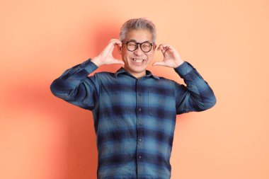 Yeşil ekose elbiseli Asyalı son sınıf öğrencisi. Gözlük takıyor. Kalp şeklinde jestler yapıyor. Turist, akıllı gündelik.