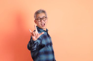 Yeşil ekose elbiseli Asyalı son sınıf öğrencisi. Gözlük takıyor. Kalp şeklinde jestler yapıyor. Turist, akıllı gündelik.