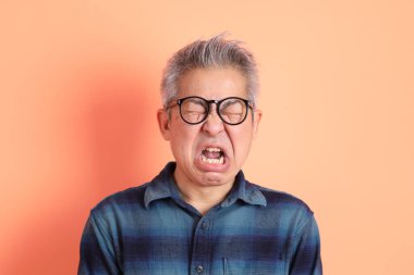 Yeşil ekose elbiseli Asyalı son sınıf öğrencisi. Gözlük takıyor. Hayal kırıklığı jesti, turuncu arka planda yalnız başına ağlıyor. Turist, akıllı gündelik.