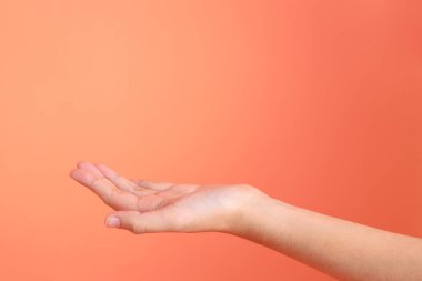 Yeşil ekose elbiseli Asyalı son sınıf öğrencisi gözlük takıyor ve turuncu arka planda kredi kartı taşıyor. Turist, akıllı gündelik.