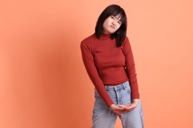 Kırmızı uzun kollu tişörtlü kısa saçlı Asyalı kadın turuncu arka planda izole edilmiş bitkinlik ve tembellik jesti. Gen Z