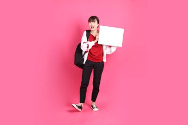 Kırmızı tişörtlü Asyalı kız öğrenci ya da günlük kıyafetler, kırmızı kalp şeklinde gömlek okul çantası taşıyor ve pembe arka planda boş tuval tutuyor. Gen Z