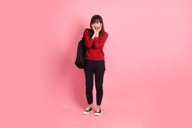 Kırmızı tişörtlü ya da sıradan giysili Asyalı kız öğrenci pembe arka planda okul çantası taşıyor. Gen Z