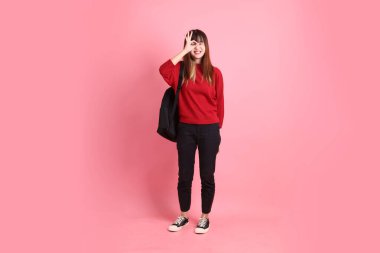 Kırmızı tişörtlü Asyalı kız öğrenci ya da günlük giysiler içinde okul çantası ve kitap taşıyorlar, tamam ya da pembe arka planda izole edilmiş olduklarını onaylıyorlar. Gen Z