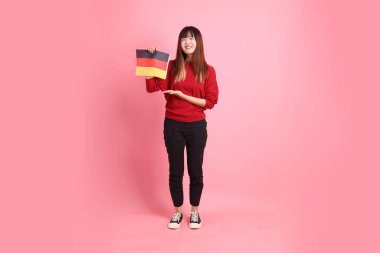 Kırmızı tişörtlü ya da sıradan giysili Asyalı kız öğrenci, pembe arka planda izole edilmiş Alman bayrağı ya da Alman bayrağı taşıyan okul çantası taşıyor. Gen Z