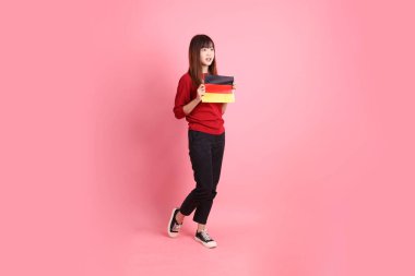 Kırmızı tişörtlü ya da sıradan giysili Asyalı kız öğrenci, pembe arka planda izole edilmiş Alman bayrağı ya da Alman bayrağı taşıyan okul çantası taşıyor. Gen Z