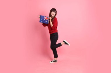 Kırmızı tişörtlü Asyalı kız öğrenci ya da günlük kıyafetler içinde ABD ya da Amerika Birleşik Devletleri ya da pembe arka planda izole edilmiş Amerikan bayrağı taşıyan okul çantası taşıyorlar. Gen Z