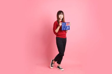 Kırmızı tişörtlü Asyalı kız öğrenci ya da günlük kıyafetler içinde ABD ya da Amerika Birleşik Devletleri ya da pembe arka planda izole edilmiş Amerikan bayrağı taşıyan okul çantası taşıyorlar. Gen Z