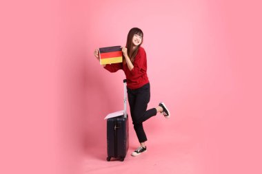 Kırmızı tişörtlü ya da sıradan giysili Asyalı kız öğrenci, pembe arka planda izole edilmiş Alman bayrağı ya da Alman bayrağı taşıyan okul çantası taşıyor. Gen Z