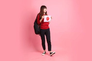 Kırmızı tişörtlü ya da sıradan giysili Asyalı bir kız öğrenci pembe arka planda Japon ya da Japon bayrağı taşıyan bir jestle okul çantası taşıyor. Gen Z