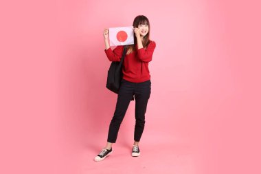 Kırmızı tişörtlü ya da sıradan giysili Asyalı bir kız öğrenci pembe arka planda Japon ya da Japon bayrağı taşıyan bir jestle okul çantası taşıyor. Gen Z