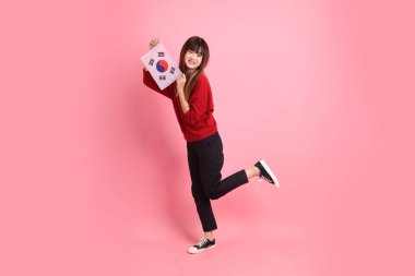 Kırmızı tişörtlü ya da sıradan giysili Asyalı kız öğrenci pembe arka planda Kore ya da Kore bayrağı saklama hareketi içeren okul çantası taşıyor. Gen Z