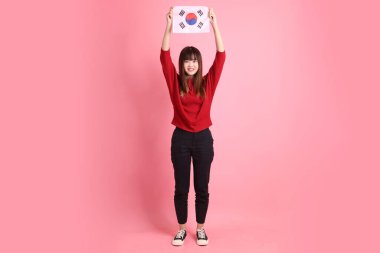 Kırmızı tişörtlü ya da sıradan giysili Asyalı kız öğrenci pembe arka planda Kore ya da Kore bayrağı saklama hareketi içeren okul çantası taşıyor. Gen Z