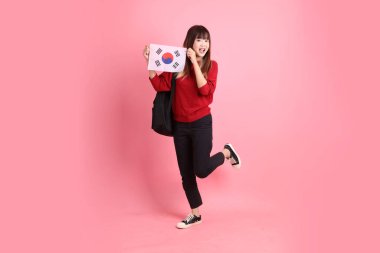 Kırmızı tişörtlü ya da sıradan giysili Asyalı kız öğrenci pembe arka planda Kore ya da Kore bayrağı saklama hareketi içeren okul çantası taşıyor. Gen Z