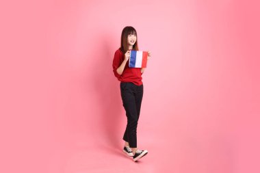 Kırmızı tişörtlü ya da sıradan giysili Asyalı kız öğrenci pembe arka planda Fransız ya da Fransız bayrağı taşıyan okul çantası taşıyor. Gen Z