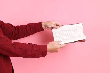 Mutlu Çin Yeni Yılı, resmi ve sıradan kırmızı tişörtlü Asyalı son sınıf öğrencisi pembe arka planda izole edilmiş bir kitabı tutuyor..