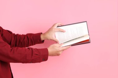 Mutlu Çin Yeni Yılı, resmi ve sıradan kırmızı tişörtlü Asyalı son sınıf öğrencisi pembe arka planda izole edilmiş bir kitabı tutuyor..