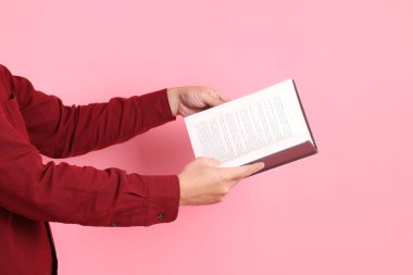 Mutlu Çin Yeni Yılı, resmi ve sıradan kırmızı tişörtlü Asyalı son sınıf öğrencisi pembe arka planda izole edilmiş bir kitabı tutuyor..