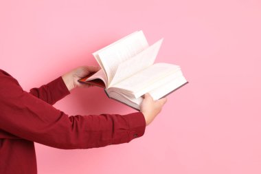 Mutlu Çin Yeni Yılı, resmi ve sıradan kırmızı tişörtlü Asyalı son sınıf öğrencisi pembe arka planda izole edilmiş bir kitabı tutuyor..