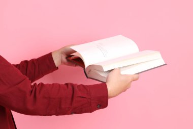 Mutlu Çin Yeni Yılı, resmi ve sıradan kırmızı tişörtlü Asyalı son sınıf öğrencisi pembe arka planda izole edilmiş bir kitabı tutuyor..