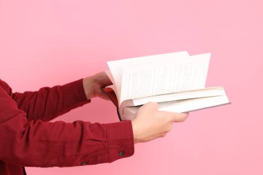 Mutlu Çin Yeni Yılı, resmi ve sıradan kırmızı tişörtlü Asyalı son sınıf öğrencisi pembe arka planda izole edilmiş bir kitabı tutuyor..