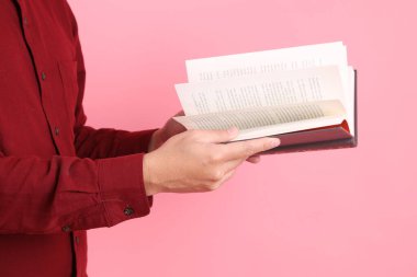 Mutlu Çin Yeni Yılı, resmi ve sıradan kırmızı tişörtlü Asyalı son sınıf öğrencisi pembe arka planda izole edilmiş bir kitabı tutuyor..