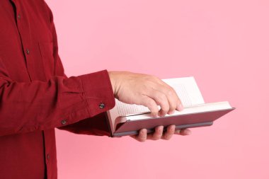 Mutlu Çin Yeni Yılı, resmi ve sıradan kırmızı tişörtlü Asyalı son sınıf öğrencisi pembe arka planda izole edilmiş bir kitabı tutuyor..