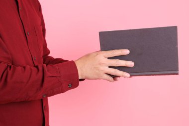 Mutlu Çin Yeni Yılı, resmi ve sıradan kırmızı tişörtlü Asyalı son sınıf öğrencisi pembe arka planda izole edilmiş bir kitabı tutuyor..