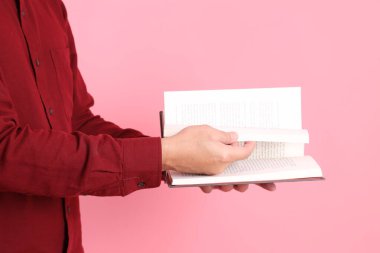 Mutlu Çin Yeni Yılı, resmi ve sıradan kırmızı tişörtlü Asyalı son sınıf öğrencisi pembe arka planda izole edilmiş bir kitabı tutuyor..